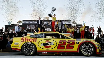 Joey Logano, driver of the #22 Shell Pennzoil Ford, celebrates with the Bill France NASCAR Cup Series Championship trophy in victory lane after winning the NASCAR Cup Series Championship Race at Phoenix Raceway on November 10, 2024 in Avondale, Arizona.